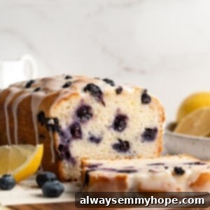 Vegan lemon blueberry bread on a wooden board with one slice cut, ready to be served.