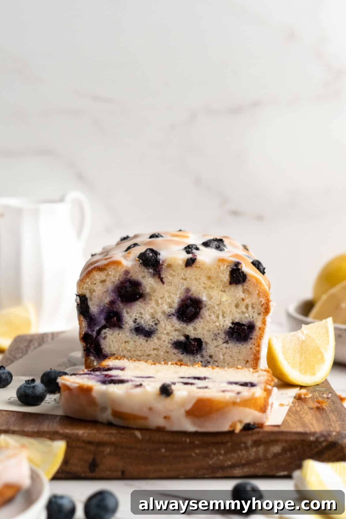 A slice of moist vegan lemon blueberry loaf on a cutting board, showcasing the tender crumb and distribution of blueberries.