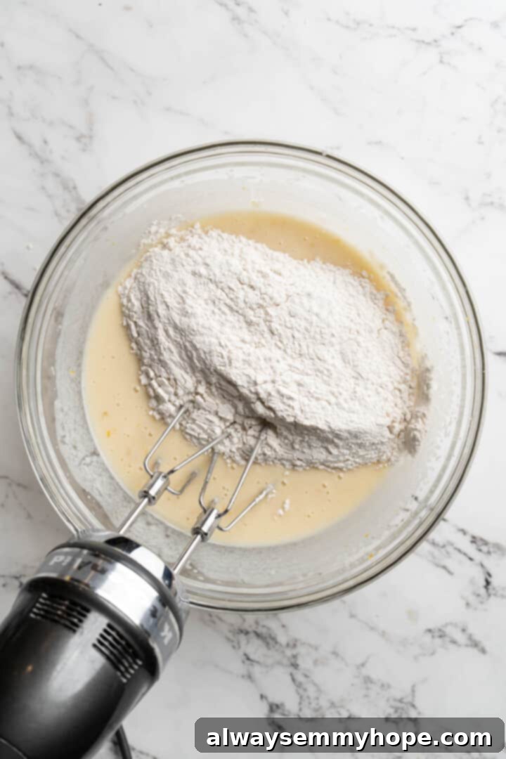 Overhead view of a mixer gently beating dry ingredients into the wet quick bread batter.