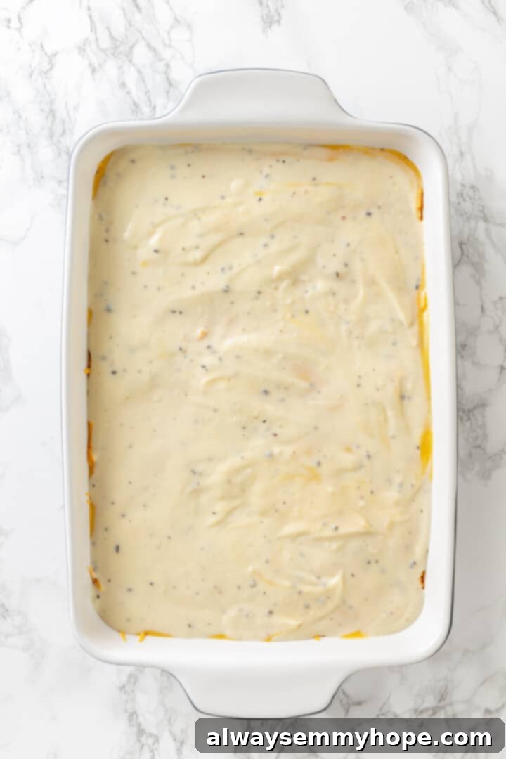 Love biscuits and gravy? You’re going to flip for biscuits and gravy casserole! The comfort food you love in a crowd-pleasing casserole. Overhead view of the fully assembled vegan biscuits and gravy casserole before baking, with all layers visible