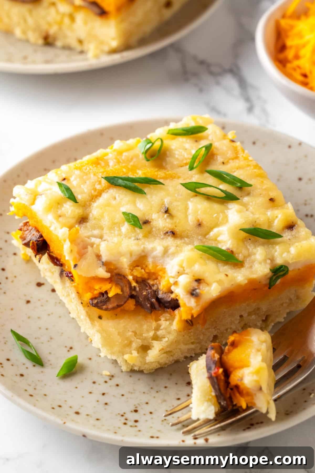 Love biscuits and gravy? You’re going to flip for biscuits and gravy casserole! The comfort food you love in a crowd-pleasing casserole. A delectable piece of vegan biscuits and gravy casserole served on a plate with a fork, ready to be savored