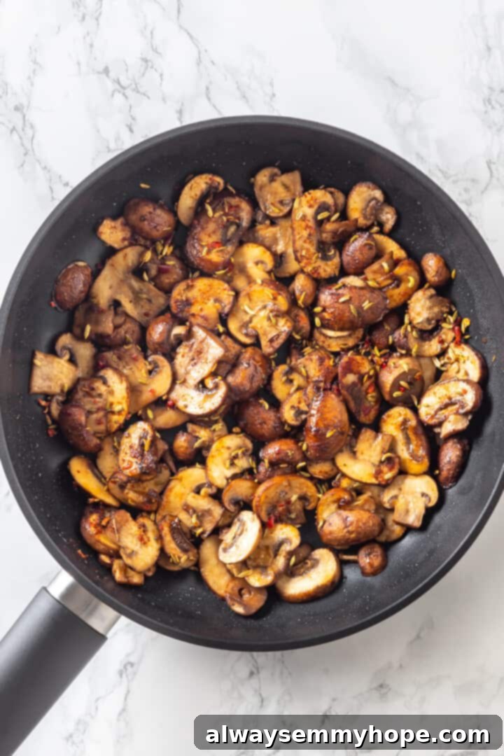 Love biscuits and gravy? You’re going to flip for biscuits and gravy casserole! The comfort food you love in a crowd-pleasing casserole. Overhead view of perfectly sauteed cremini mushrooms in a skillet, seasoned with fragrant spices
