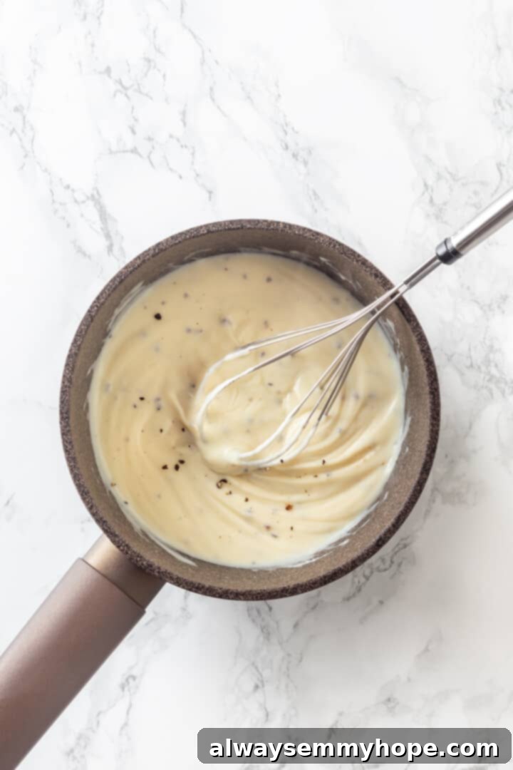 Love biscuits and gravy? You’re going to flip for biscuits and gravy casserole! The comfort food you love in a crowd-pleasing casserole. Overhead view of creamy vegan gravy being whisked to perfection in a saucepan, showing its smooth consistency
