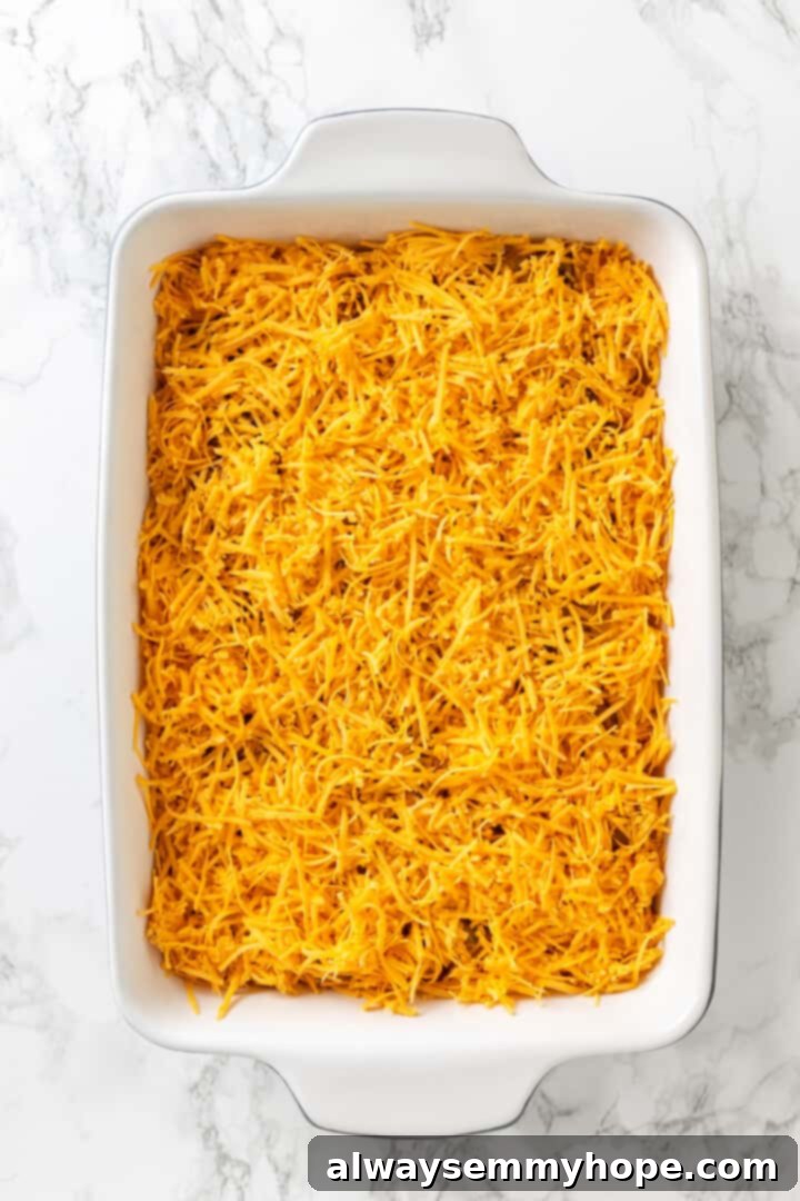 Love biscuits and gravy? You’re going to flip for biscuits and gravy casserole! The comfort food you love in a crowd-pleasing casserole. Overhead view of a generous layer of shredded vegan cheddar cheese sprinkled over the mushroom layer in the casserole