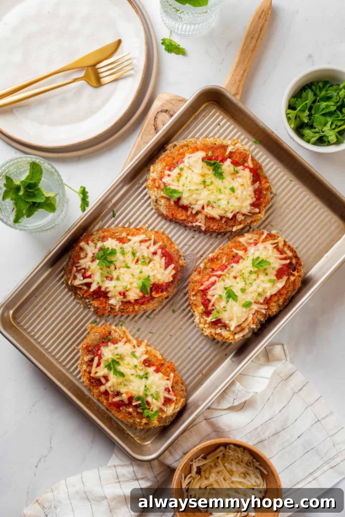 Overhead view of 4 chicken parmesan cutlets on baking sheet