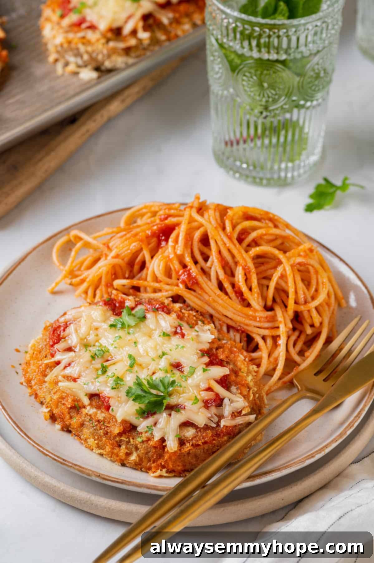 Chicken parmesan on plate with spaghetti, fork, and knife