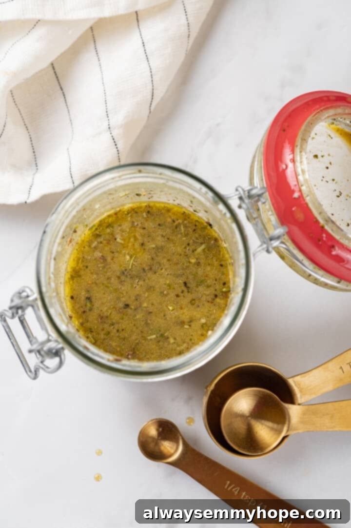 Close-up overhead shot of homemade Dijon vinaigrette dressing in a small glass jar, ready to be shaken.