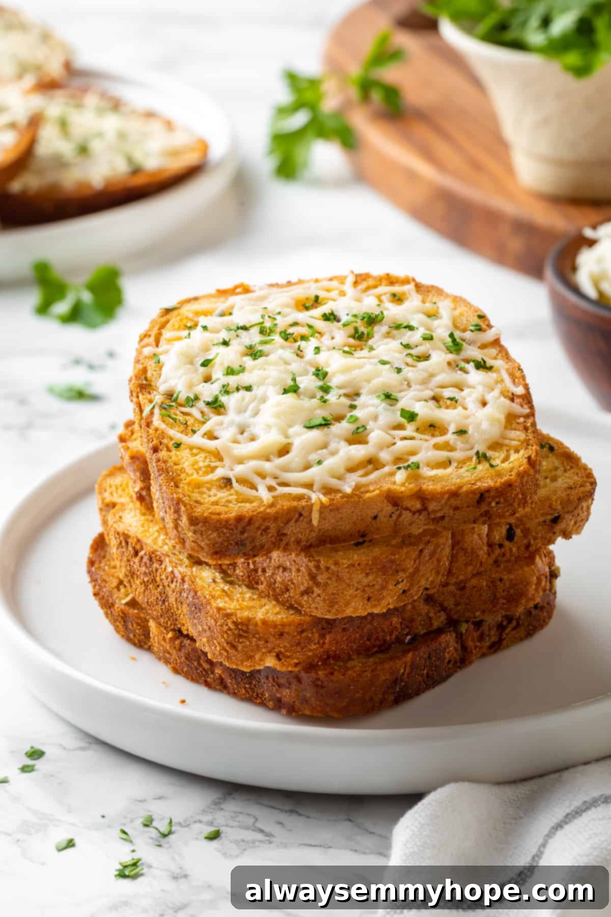 A stack of cheesy vegan Texas toast slices on a white plate, showcasing melted vegan cheddar or mozzarella cheese.
