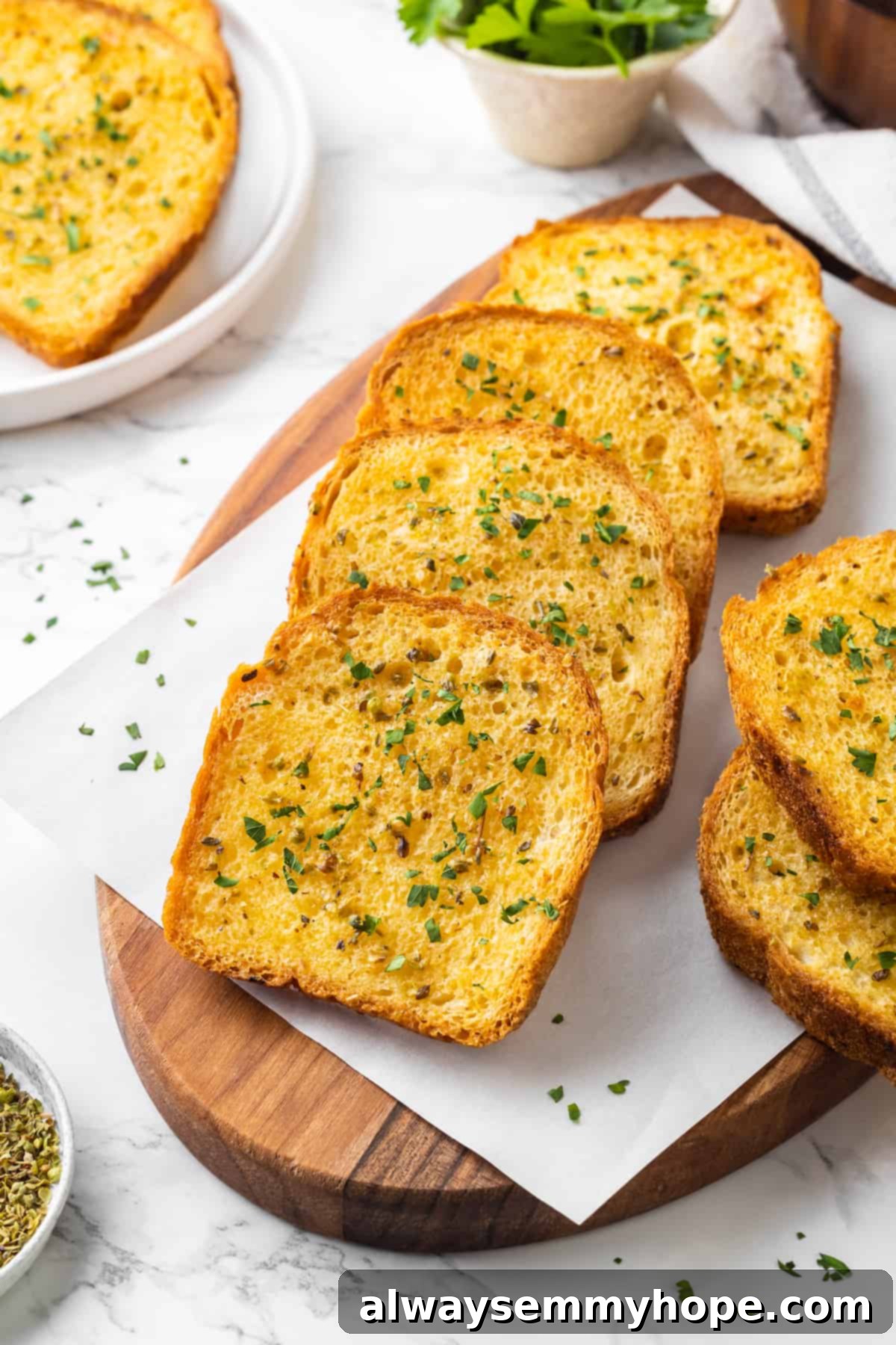 Several slices of vegan Texas toast neatly arranged on a parchment-lined wooden board, showing off their golden-brown color and buttery texture.
