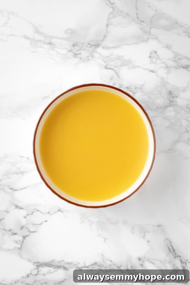 Overhead view of melted vegan butter in a small white bowl, showing its smooth, liquid texture.