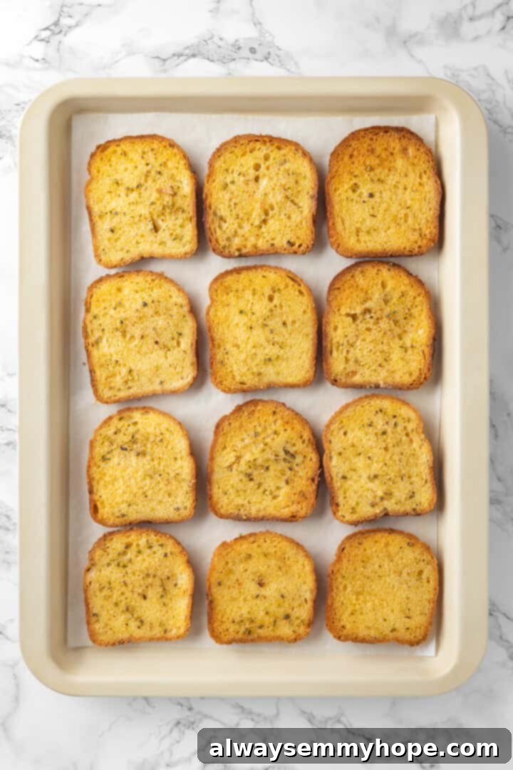 Overhead view of twelve slices of vegan Texas toast on a sheet pan, both sides buttered and ready for the oven.