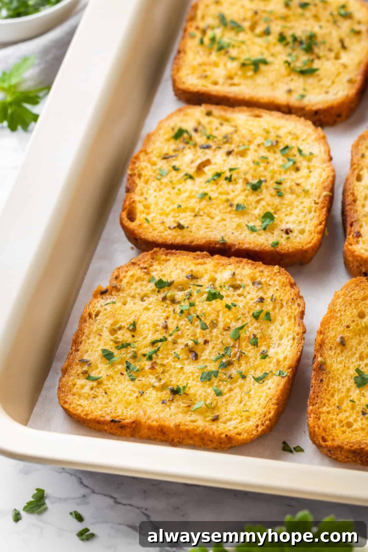 Slices of perfectly golden-brown vegan Texas toast cooling on a baking sheet after being removed from the oven.