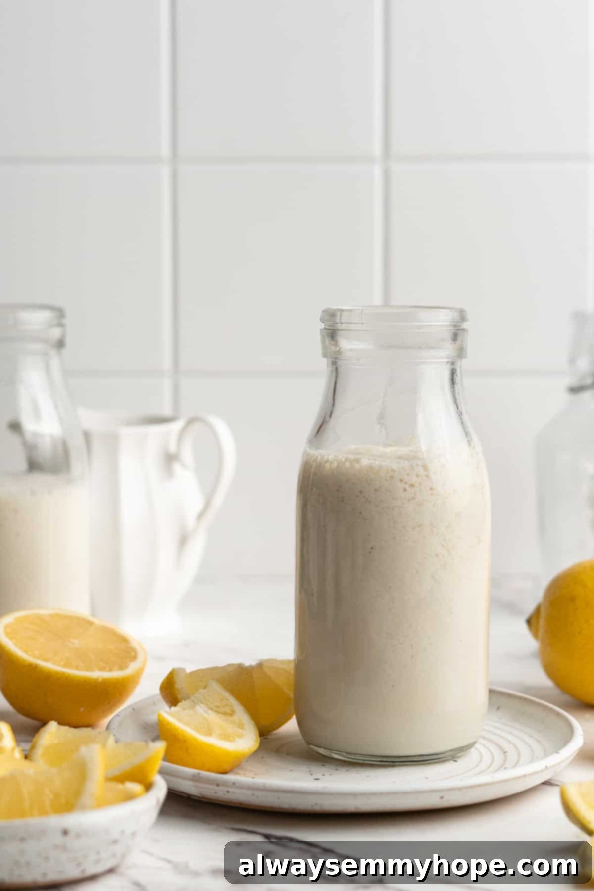 Elevate your baking with this easy vegan buttermilk recipe. Made with only two simple ingredients you already have! A glass jar filled with freshly made vegan buttermilk, placed on a rustic plate with vibrant sliced lemons, ready for baking.