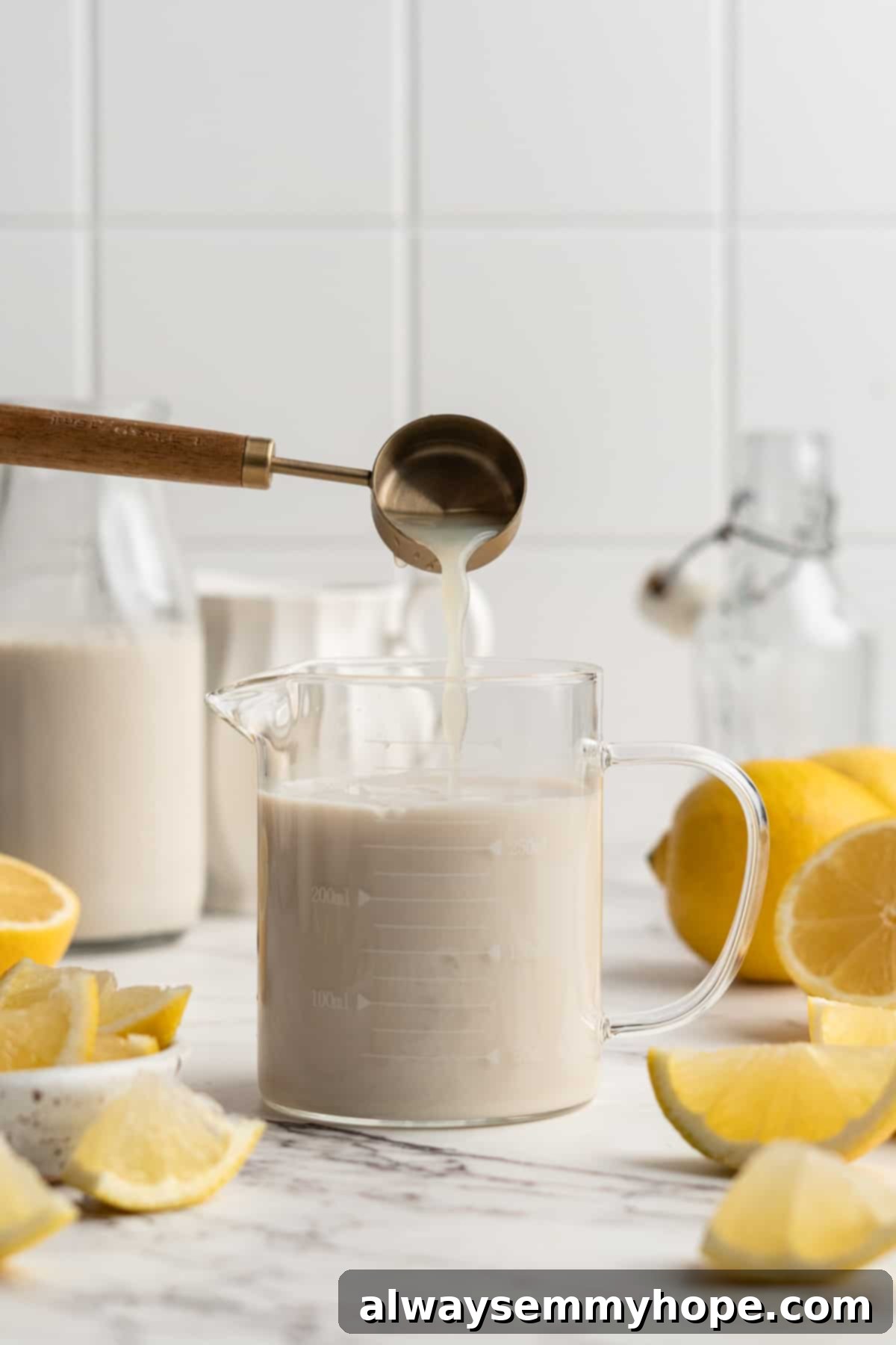 The quick and easy process of making vegan buttermilk at home with minimal steps. Pouring fresh lemon juice into a liquid measuring cup filled with soy milk, the first step in making vegan buttermilk.