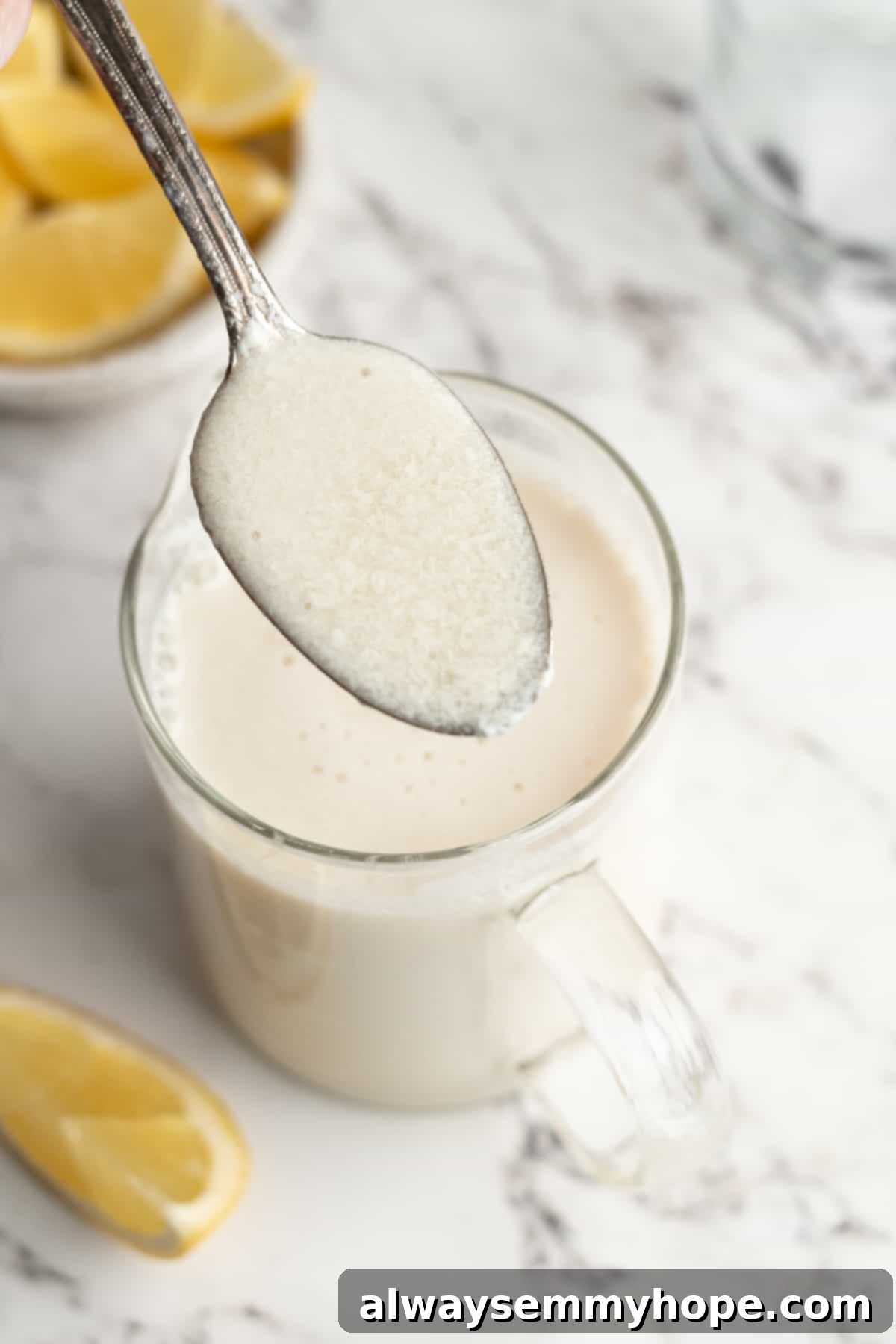 Visually assess the perfect, creamy consistency of your freshly made vegan buttermilk. A spoonful of thick, white vegan buttermilk held over a liquid measuring cup, demonstrating its ideal consistency.