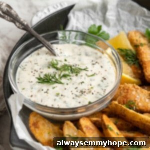 Bowl of tartar sauce garnished with fresh dill on plate of fish and chips