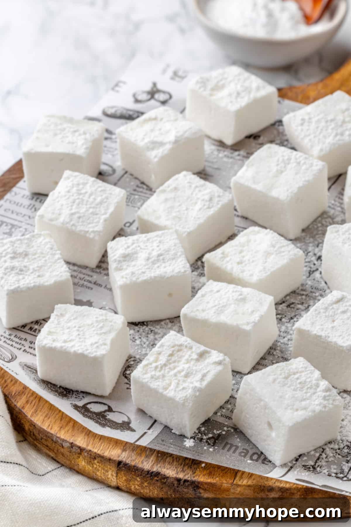 Vegan marshmallows arranged on newspaper-lined cutting board