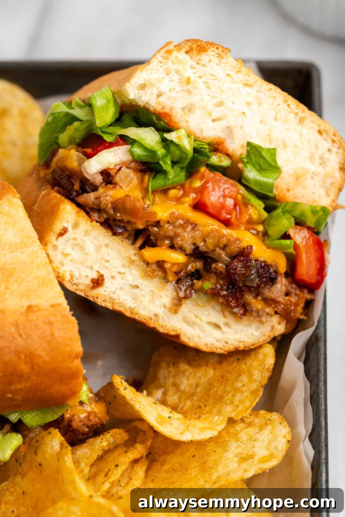 The chopped cheese sandwich is a NYC classic—and now you can make your own vegan version at home! You'll love this easy, delicious recipe. Close up of a vegan chopped cheese sandwich cut in half, showcasing melted cheese and fresh toppings