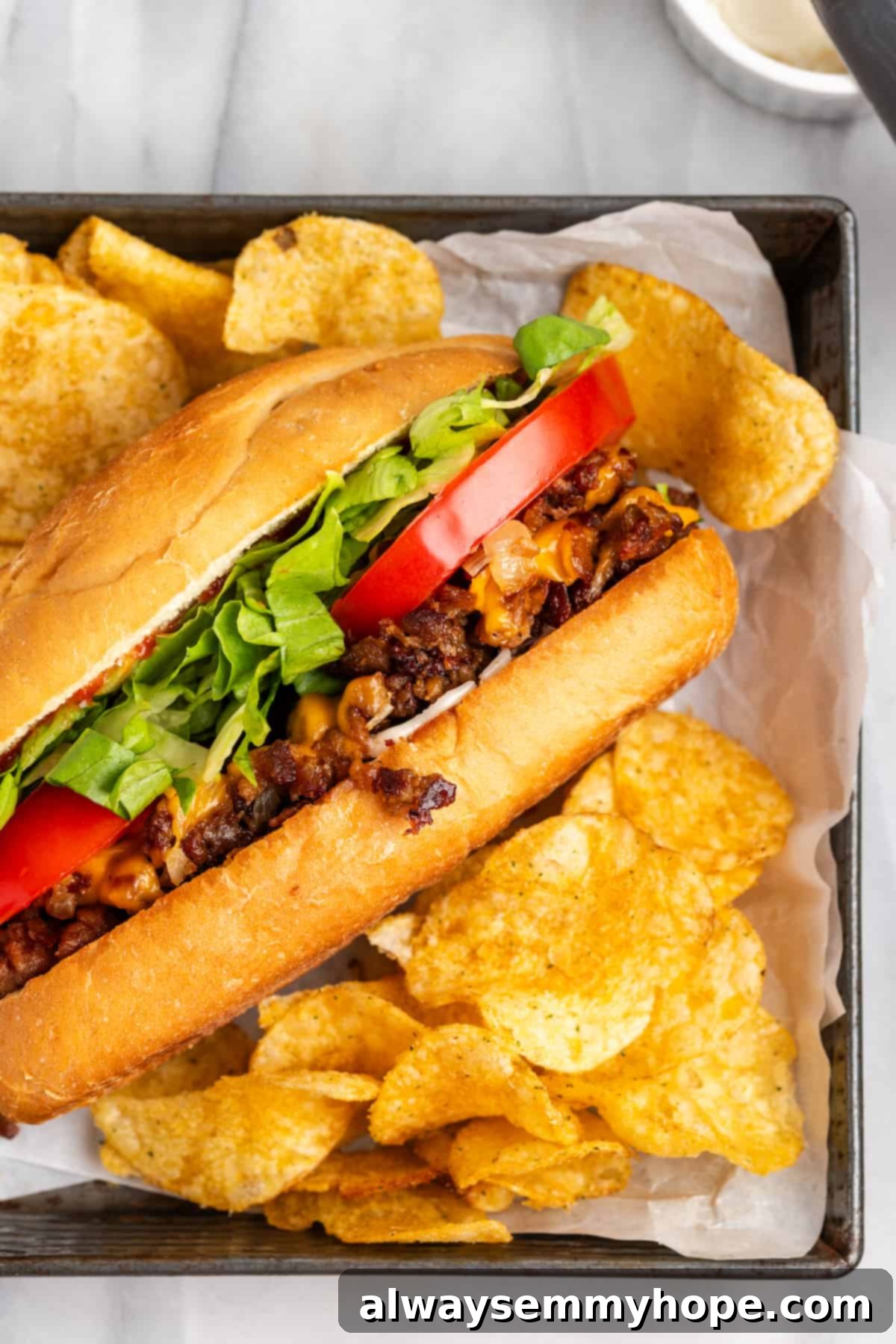 The chopped cheese sandwich is a NYC classic—and now you can make your own vegan version at home! You'll love this easy, delicious recipe. Top view of a Vegan Chopped Cheese sandwich served with a side of potato chips