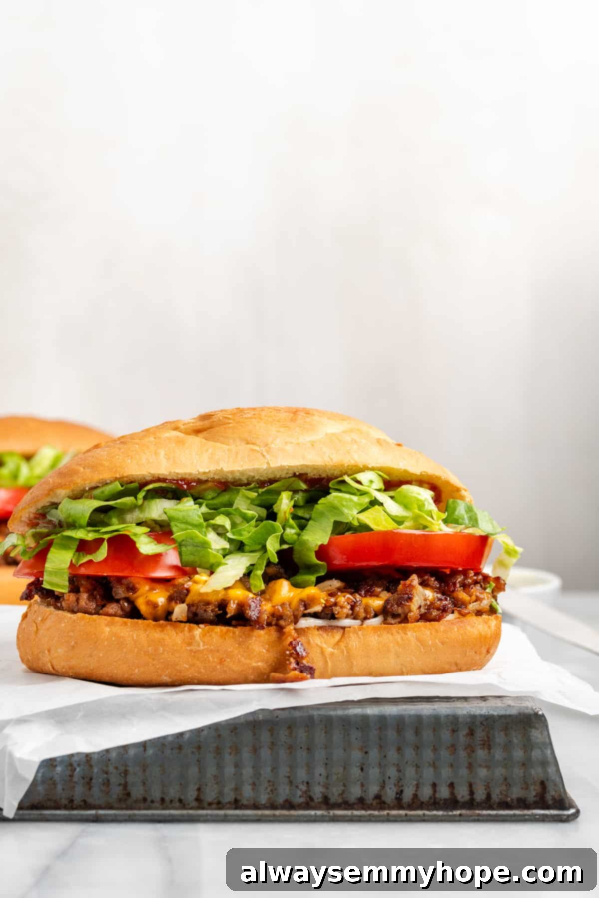 The chopped cheese sandwich is a NYC classic—and now you can make your own vegan version at home! You'll love this easy, delicious recipe. Side view of a Vegan Chopped Cheese Sandwich, showing the layers of filling and toppings
