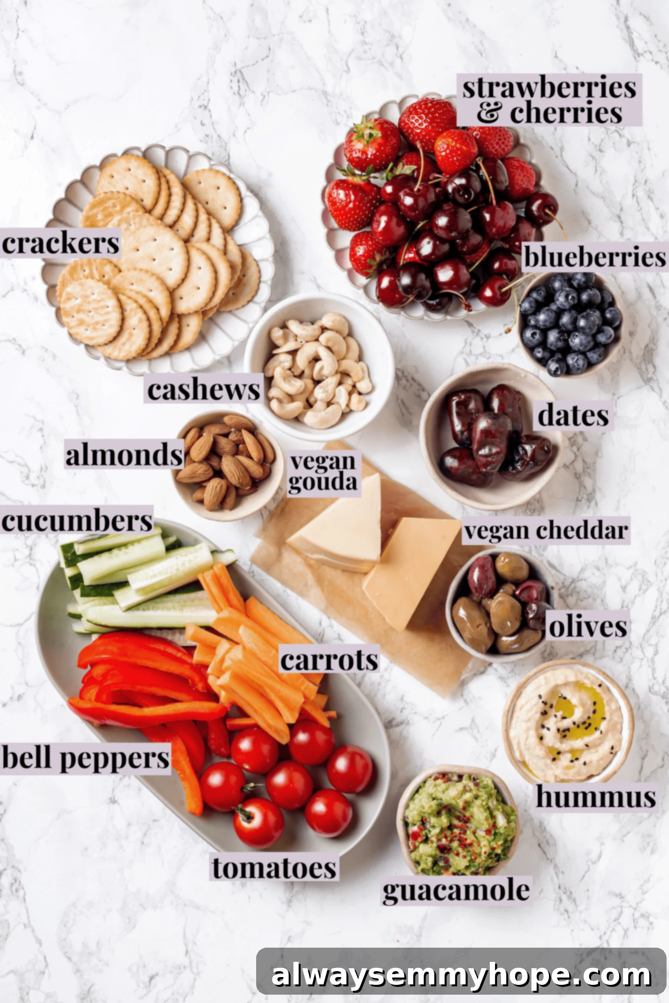 Overhead flat lay of all the fresh and packaged ingredients laid out for making a vegan charcuterie board, with labels identifying each category.