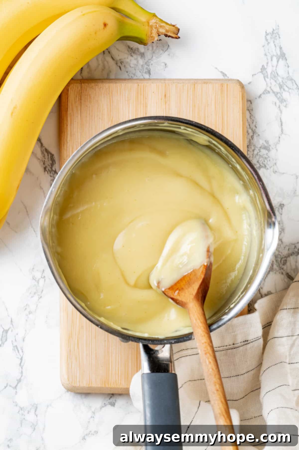 Overhead view of the creamy vegan filling simmering in a saucepan with a wooden spoon.