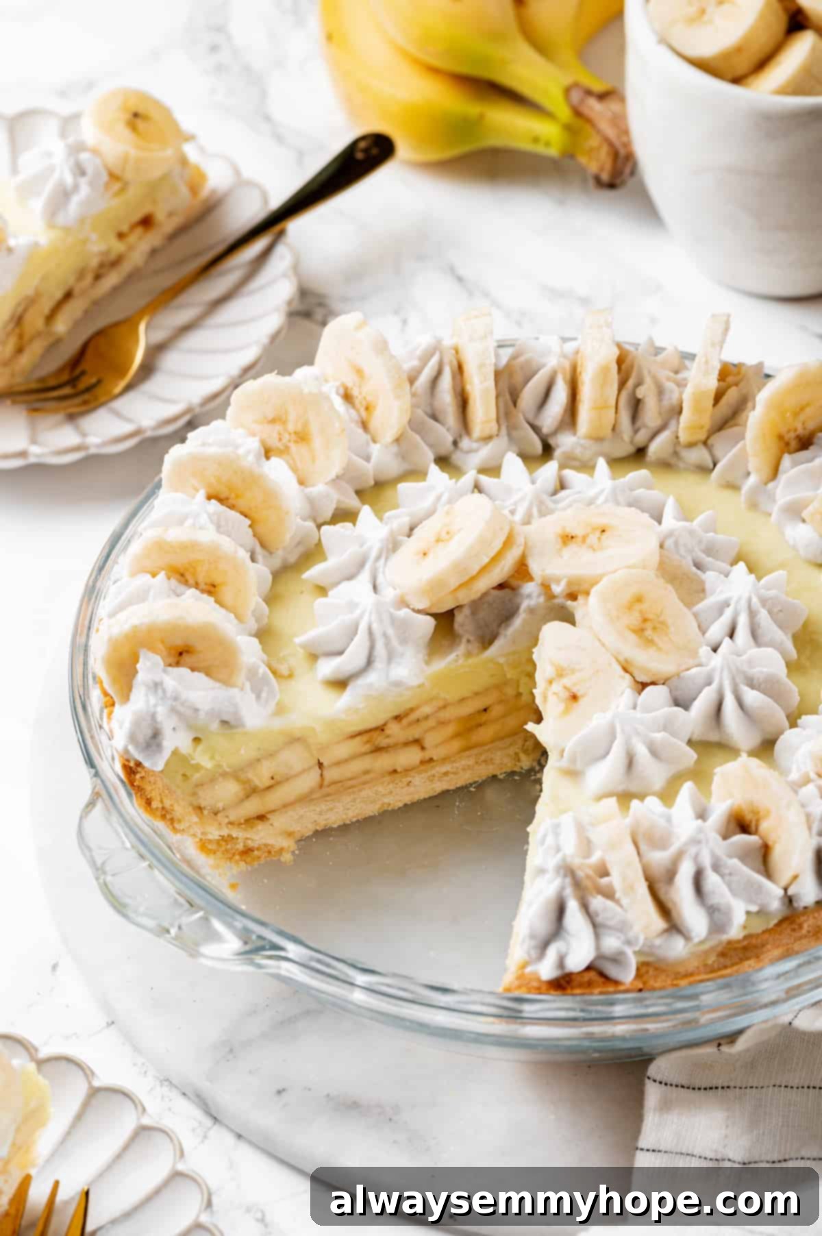 Vegan banana cream pie in a glass pie plate with two perfect slices removed, showing the layers.
