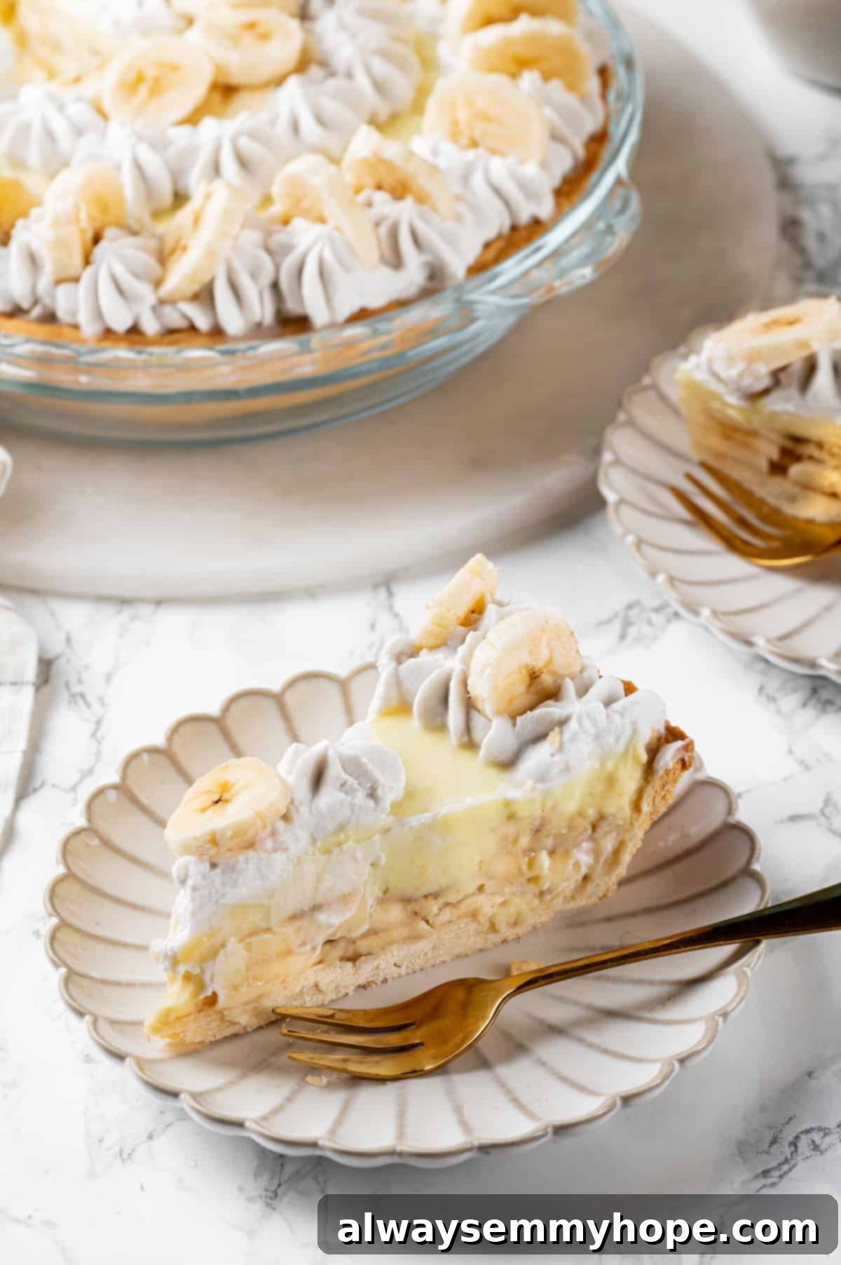 A close-up of a single slice of vegan banana cream pie on a plate with a fork, with the rest of the pie blurred in the background.