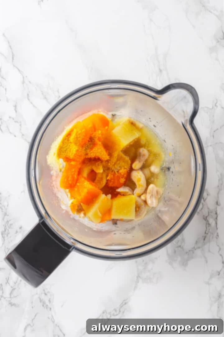Overhead view of all ingredients for the vegan cheese sauce placed in a blender jar, ready to be blended.