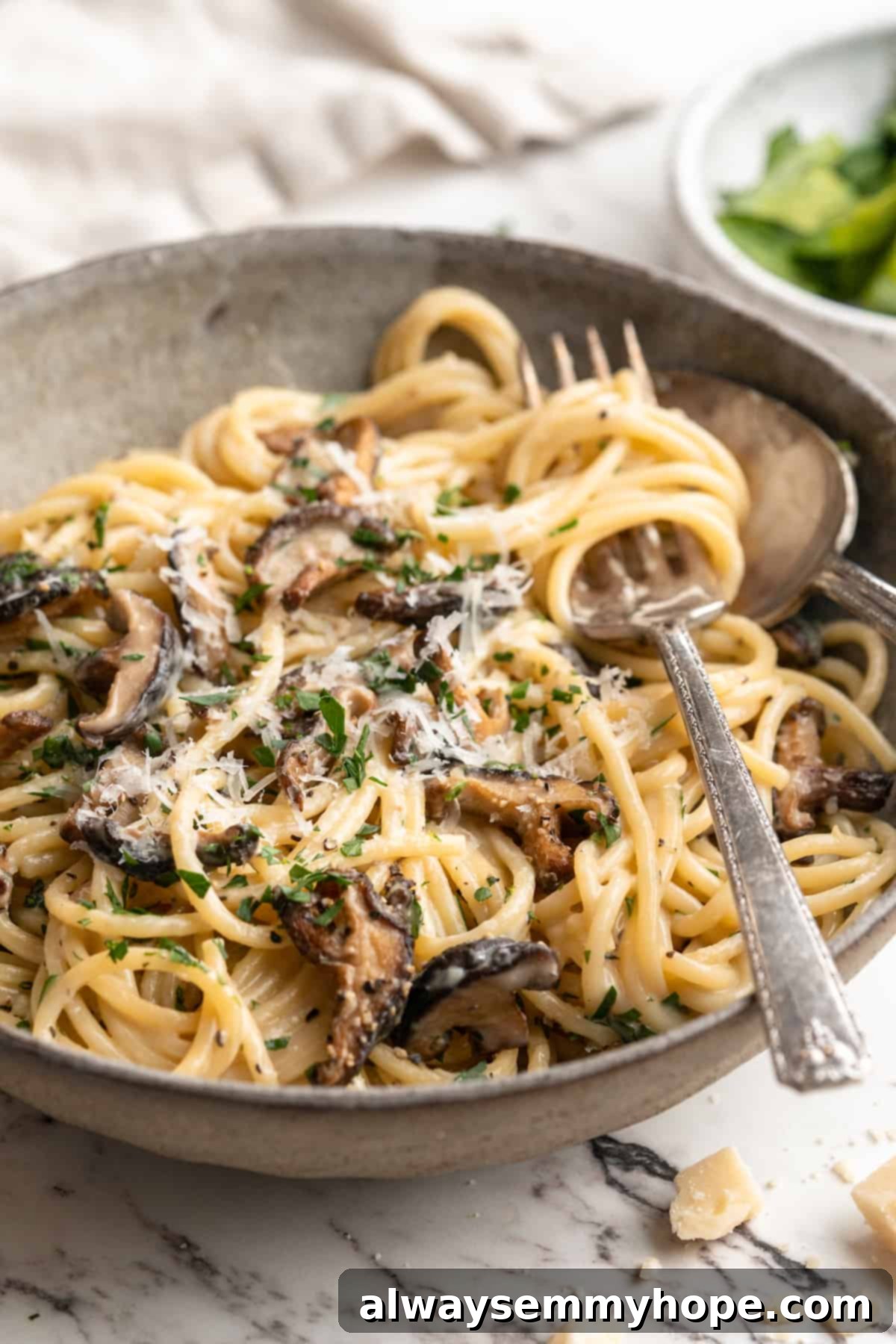 Miso butter pasta in bowl with fork and spoon, garnished with fresh parsley.