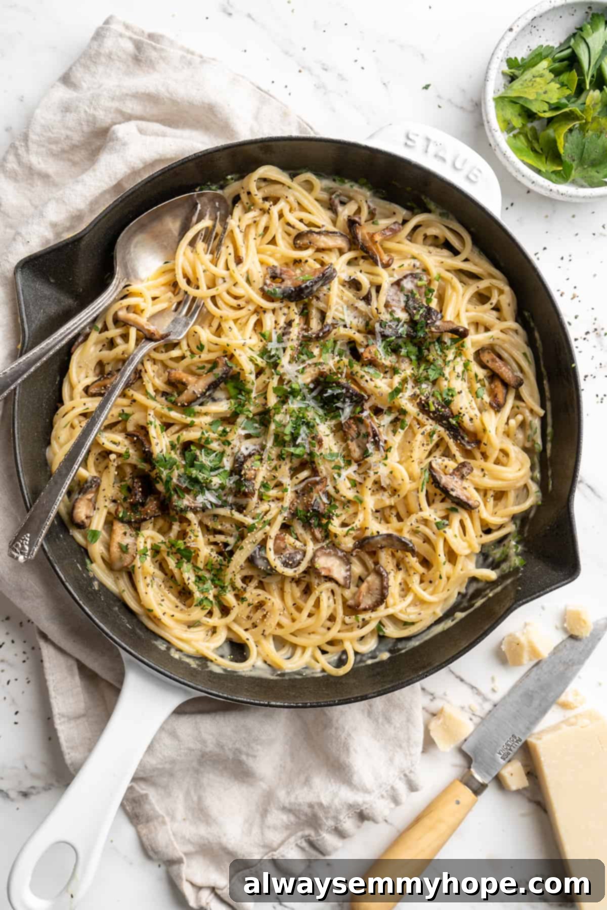 Overhead view of miso butter pasta in skillet with fork and spoon, garnished with fresh parsley.