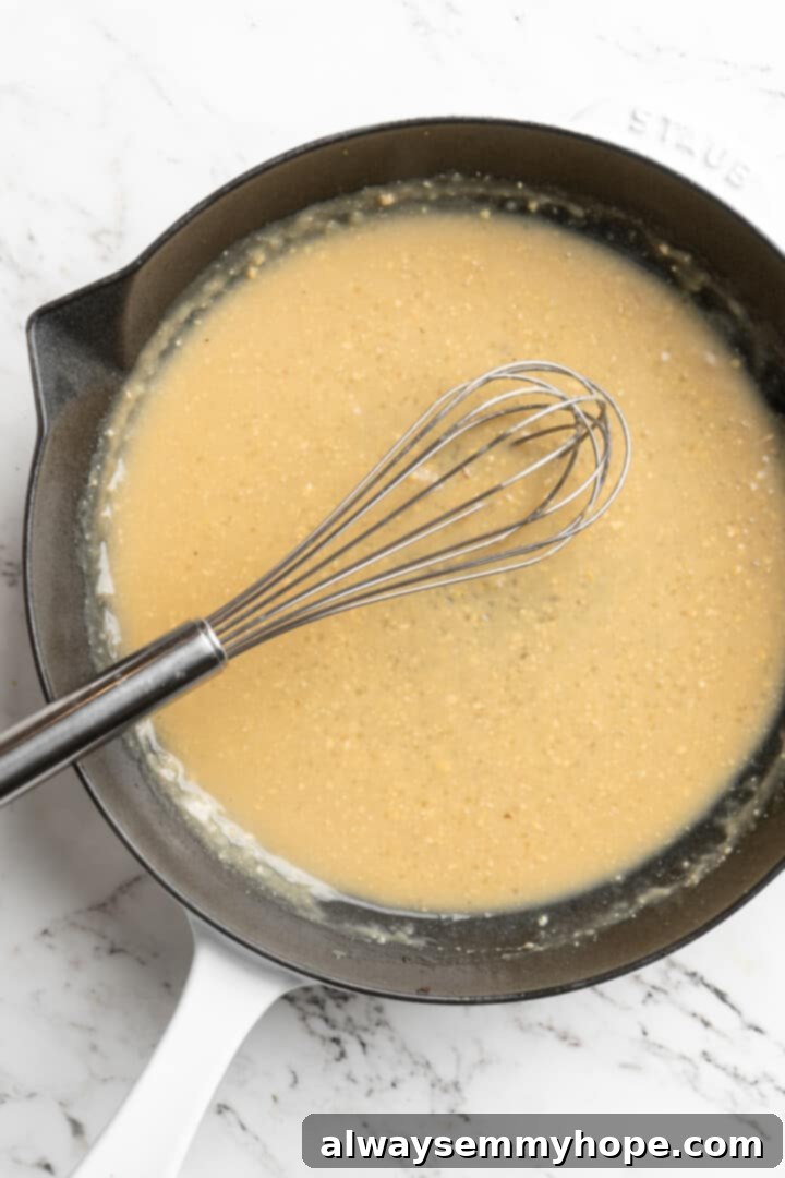 Overhead view of whisk in skillet of miso butter sauce, dissolving miso paste into pasta water.