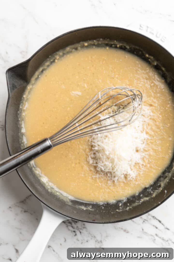 Overhead view of sauce for miso butter pasta in skillet after adding vegan Parmesan, creating a creamy and cheesy base.