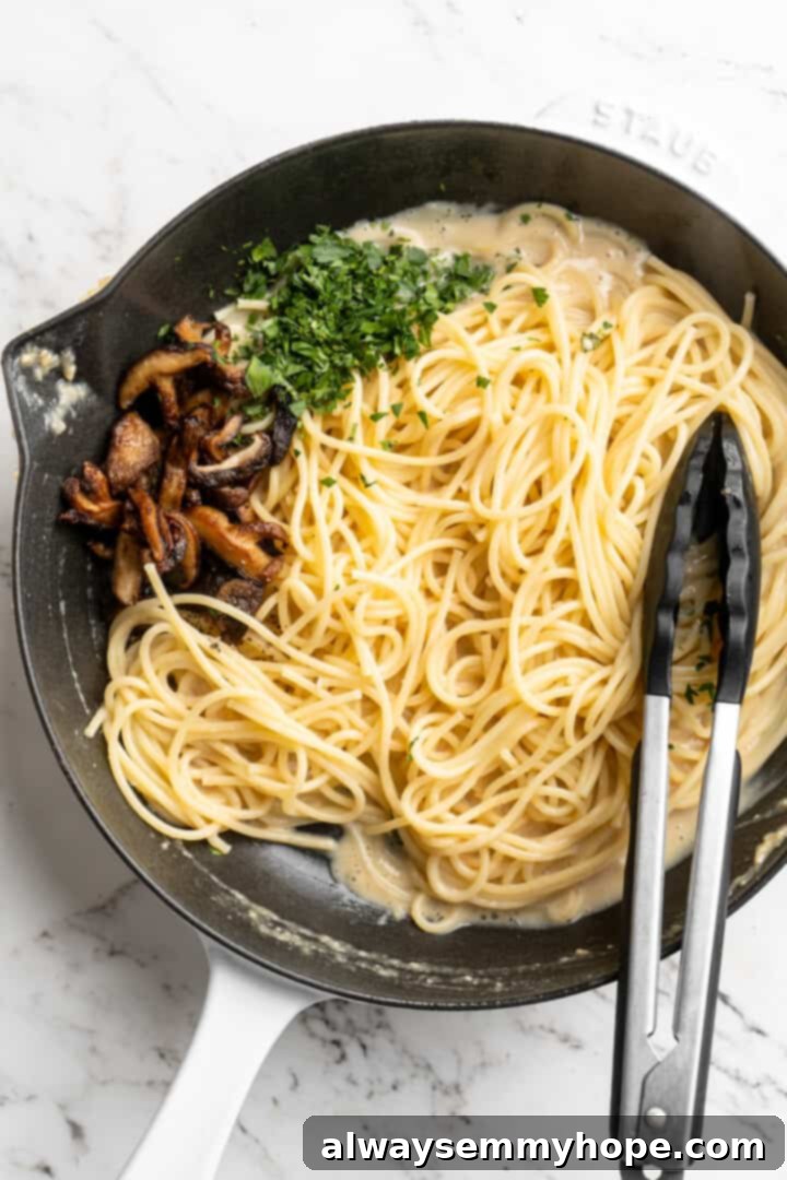 Overhead view of miso butter pasta in skillet after adding mushrooms and parsley, ready to be tossed.