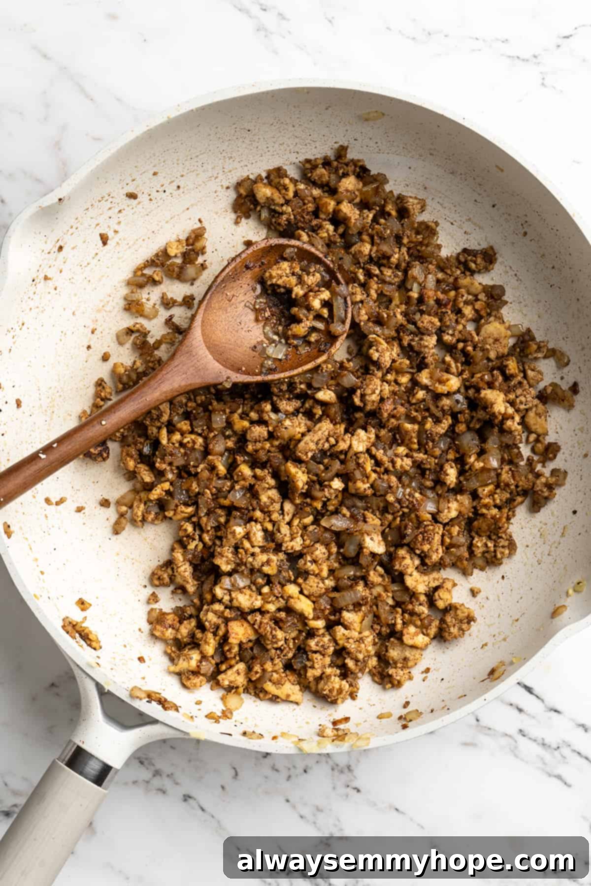 Overhead view of sambusa filling in skillet with wooden spoon