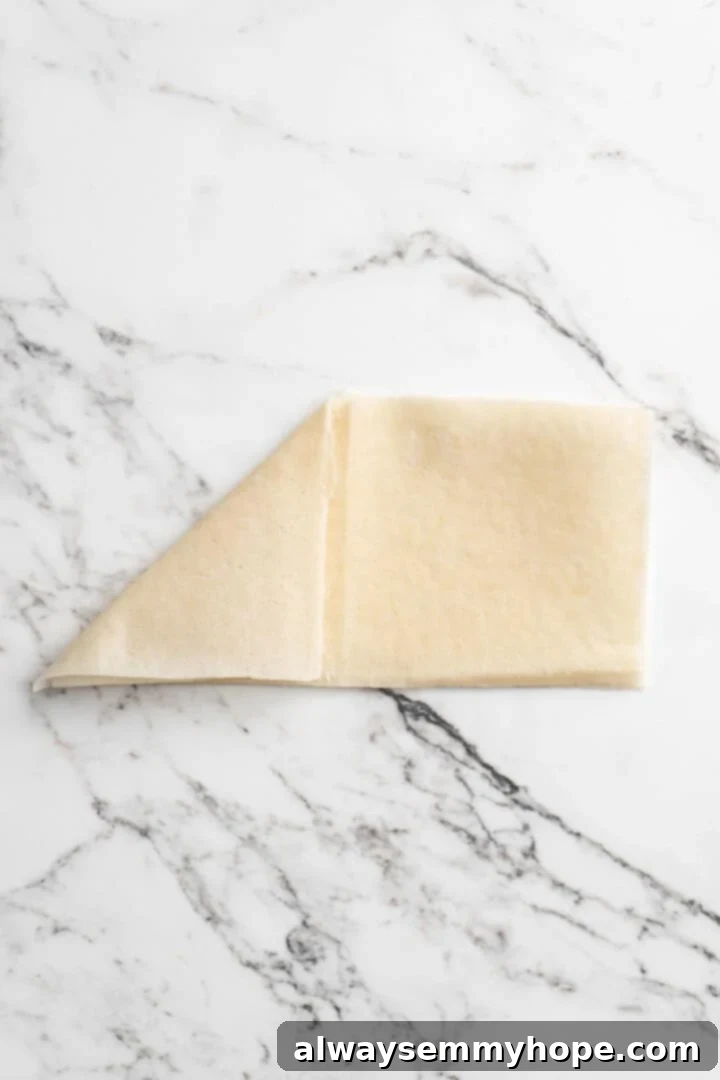 Overhead view showing process of folding sambusa wrapper