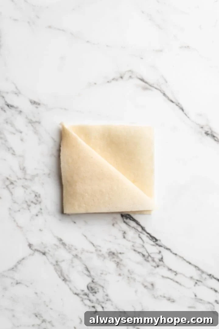 Overhead view showing process of folding sambusa wrapper