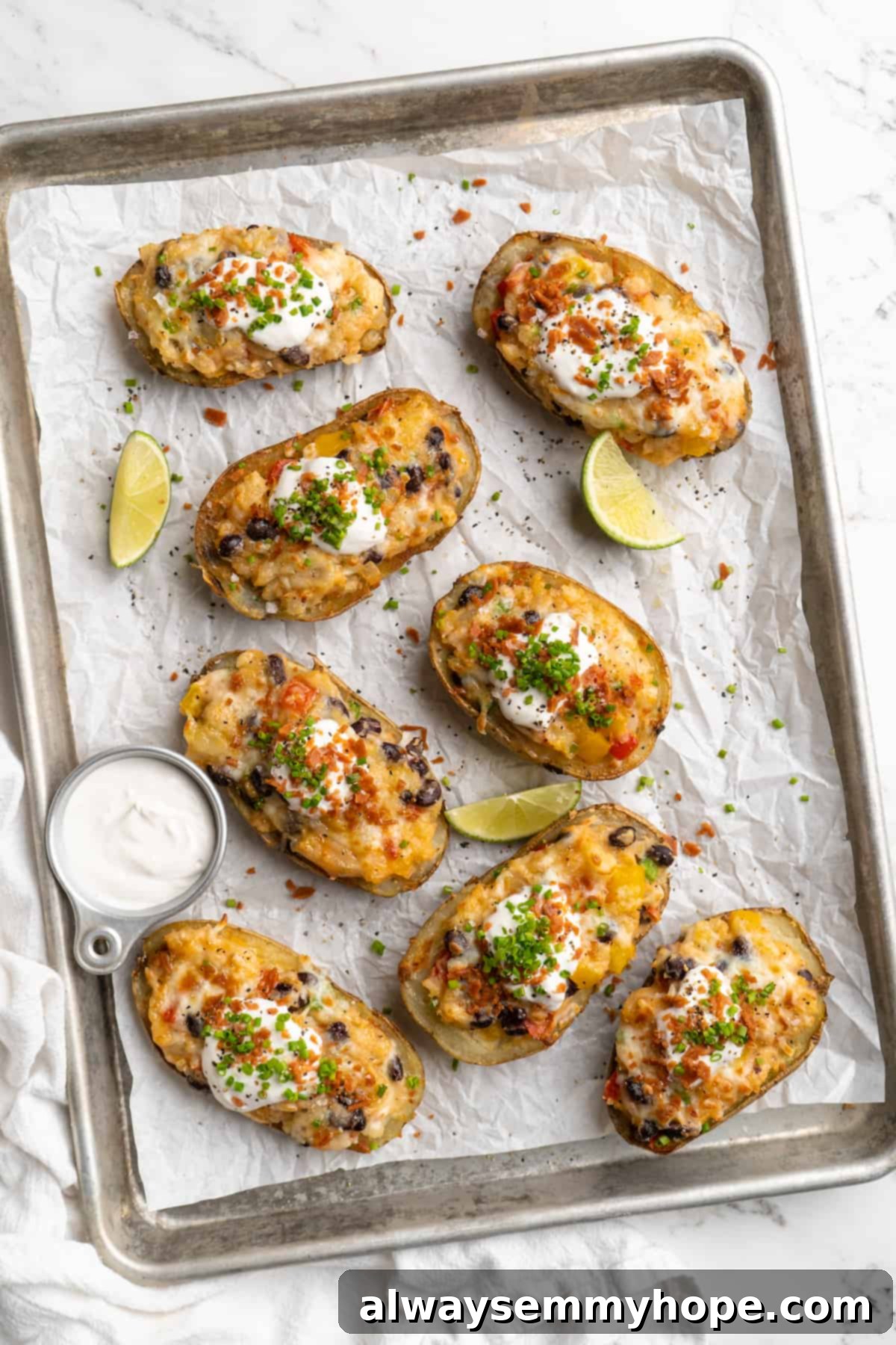 Overhead view of loaded potato skins arranged on parchment-lined baking sheet