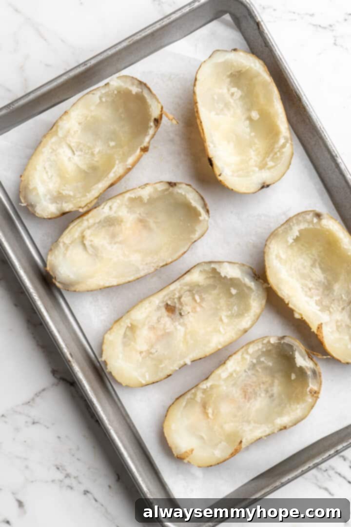Overhead view of hollowed out potato halves on baking sheet