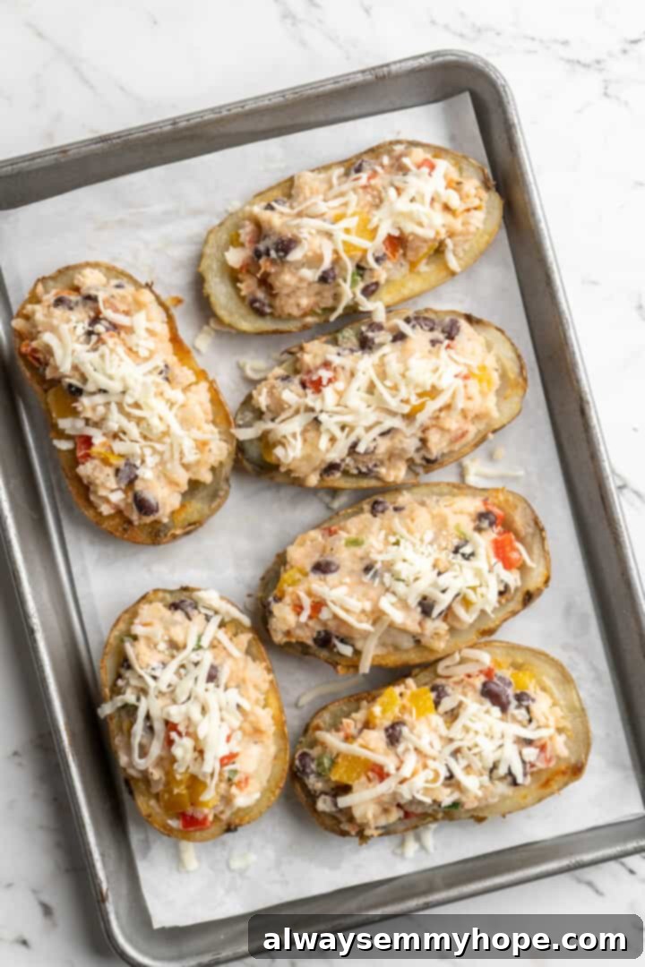 Overhead view of unbaked loaded potato skins on parchment-lined baking sheet