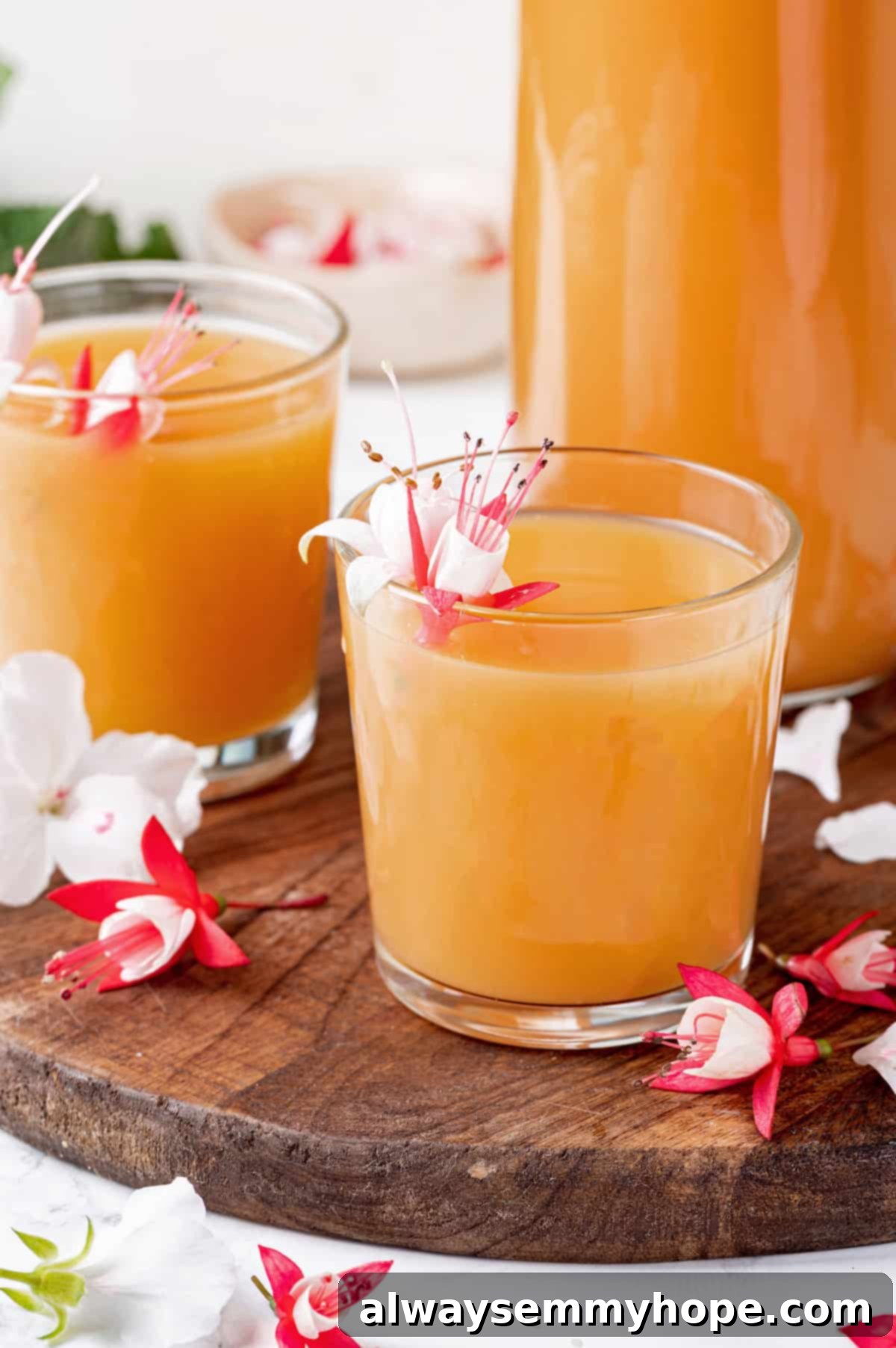 Two juice glasses of POG juice with tropical flowers for garnish