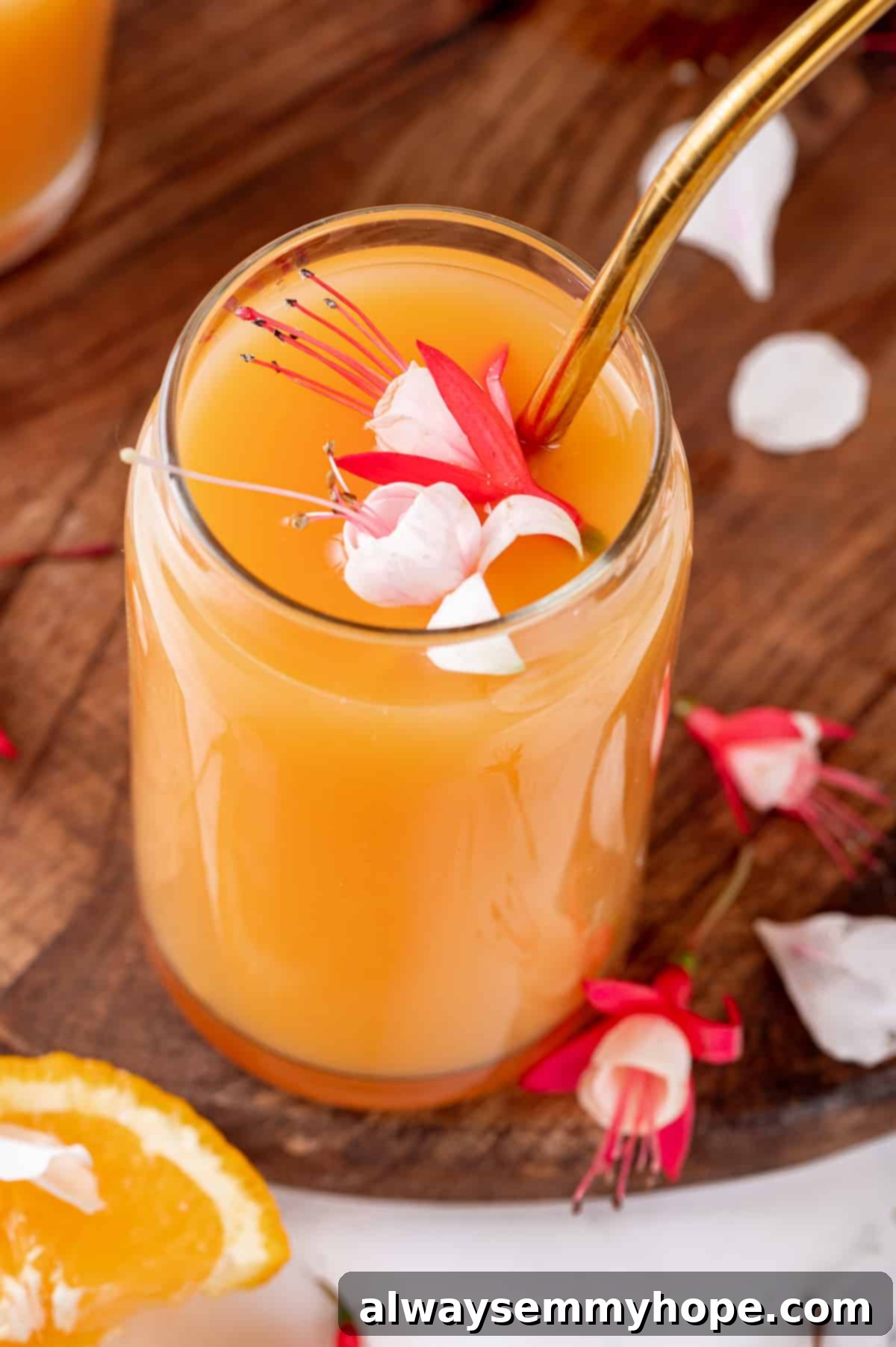 Glass of POG juice with gold straw and flower garnish