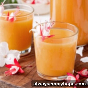 Two juice glasses of POG juice with tropical flowers for garnish