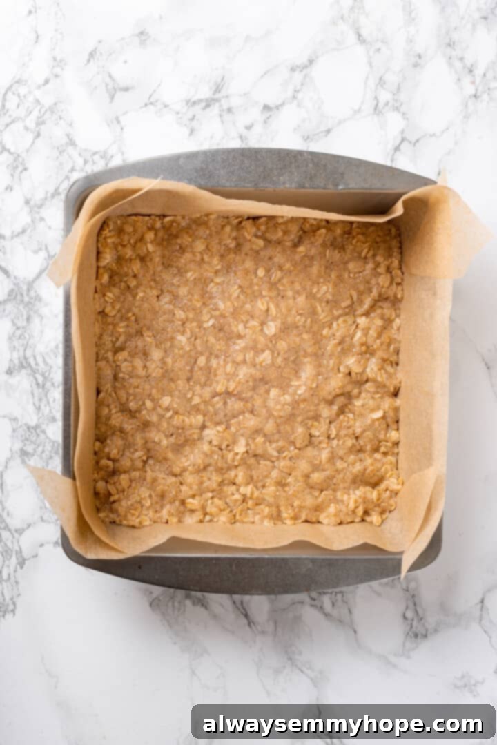 Baked Oat Crust Base Overhead view of the pressed oat crust base in a parchment-lined baking pan