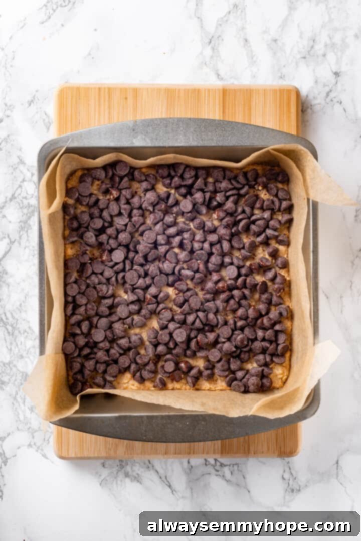 Adding Chocolate Chips to Carmelitas Overhead view of chocolate chips sprinkled over the baked oat crust