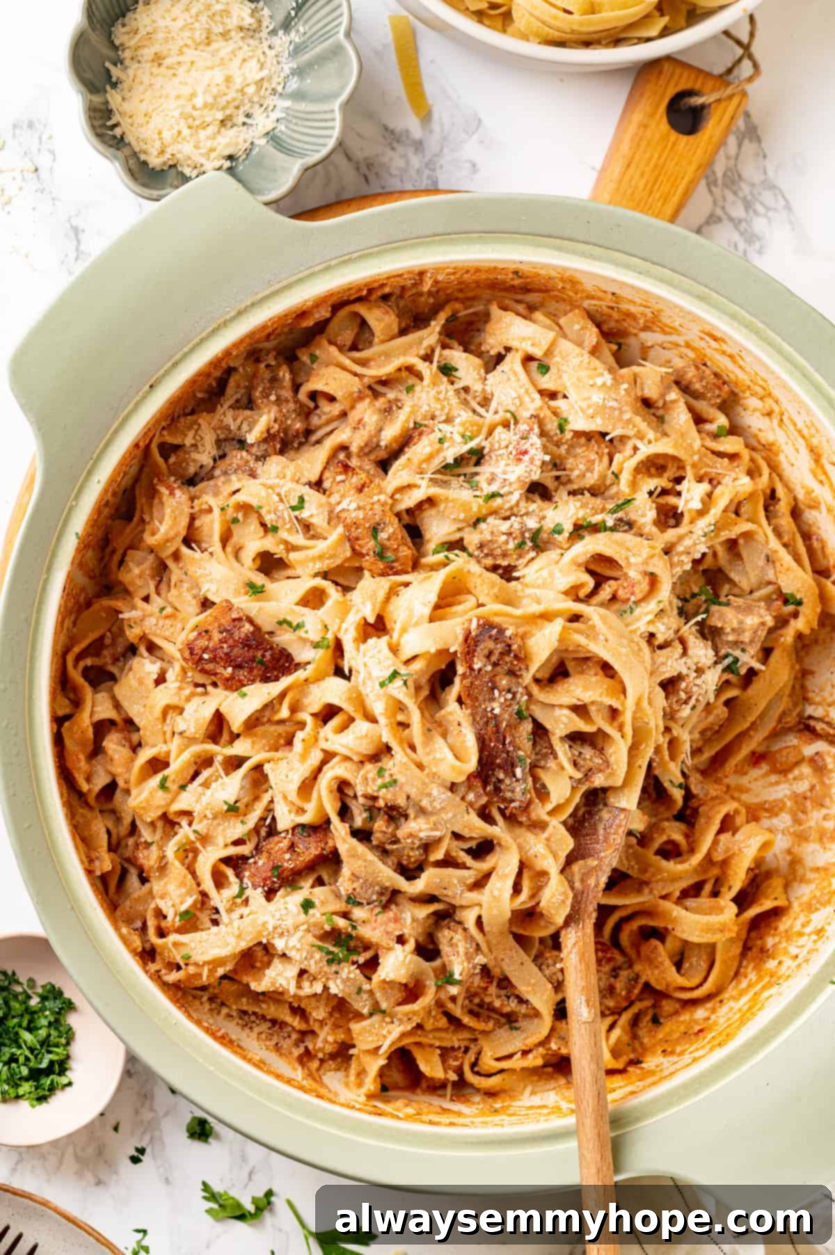 Overhead view of creamy Cajun chicken pasta in a pot with a wooden spoon, ready to be served