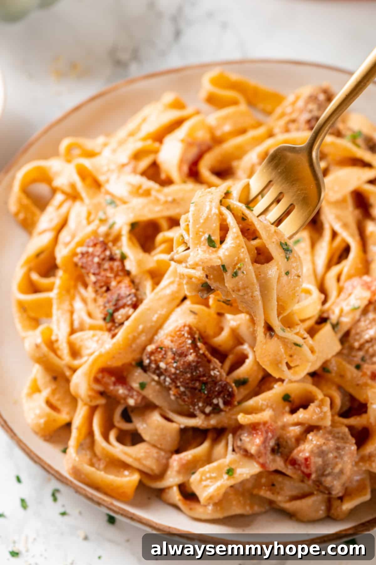 Gold fork holding a bite of Cajun chicken pasta over a plate, showing the creamy texture