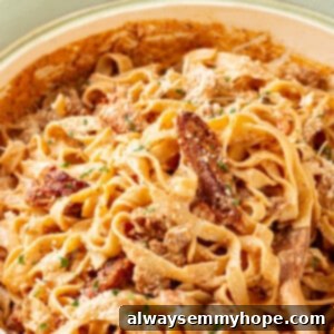 Cajun chicken pasta in large ceramic skillet with wooden spoon