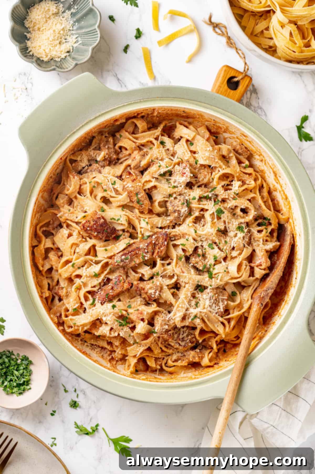 Overhead view of Cajun chicken pasta simmering in a large pot with a wooden spoon