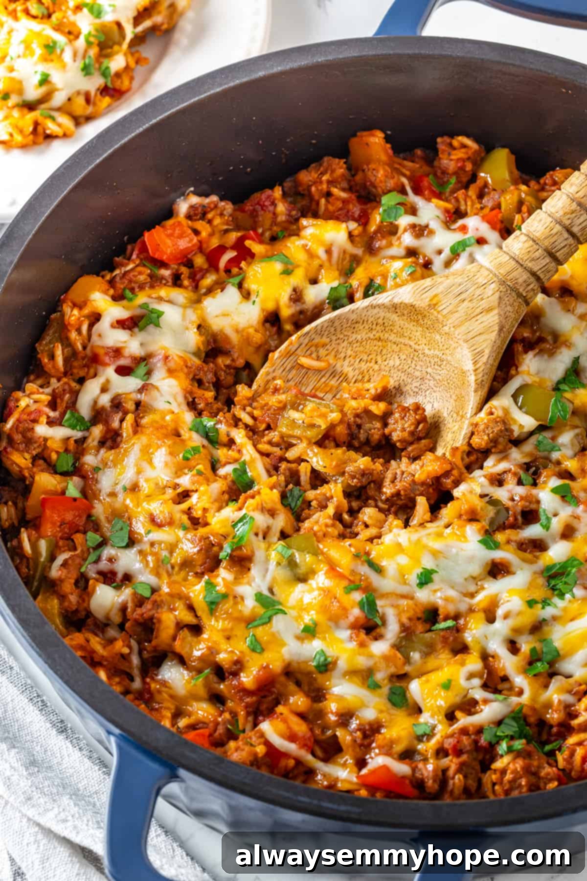 Vegan stuffed pepper casserole in a skillet with a wooden spoon, ready for serving. Vegan stuffed pepper casserole in skillet with wooden spoon